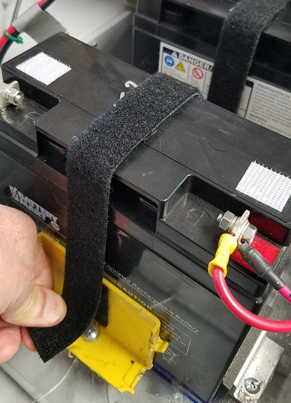 Velcro used to secure strap to modified electrical boxes on either side of the battery keeps the battery in place.