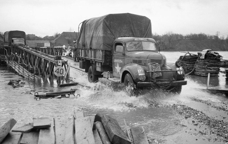 British_supply_trucks_crossing_a_Bailey_bridge_over_the_Maas_in_full_flood_at_Maeseyk_in_Holland,_25_November_1944._B12119.jpg