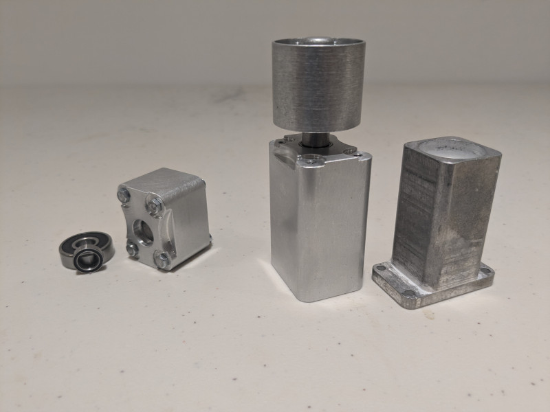 From left to right: Replacement MR128-2RS front bearing with the original 608 ZZ still being used in the rear, Replacement short return roller with cosmetic M3 hex screws mounted, Assembled replacement long return roller without cosmetic screws mounted, and the original long return roller housing for reference.